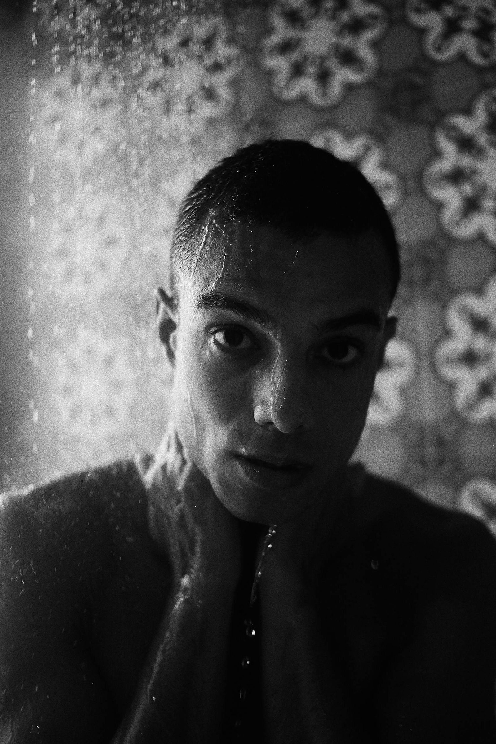 Dramatic black and white portrait capturing a man's intense expression while in the shower.