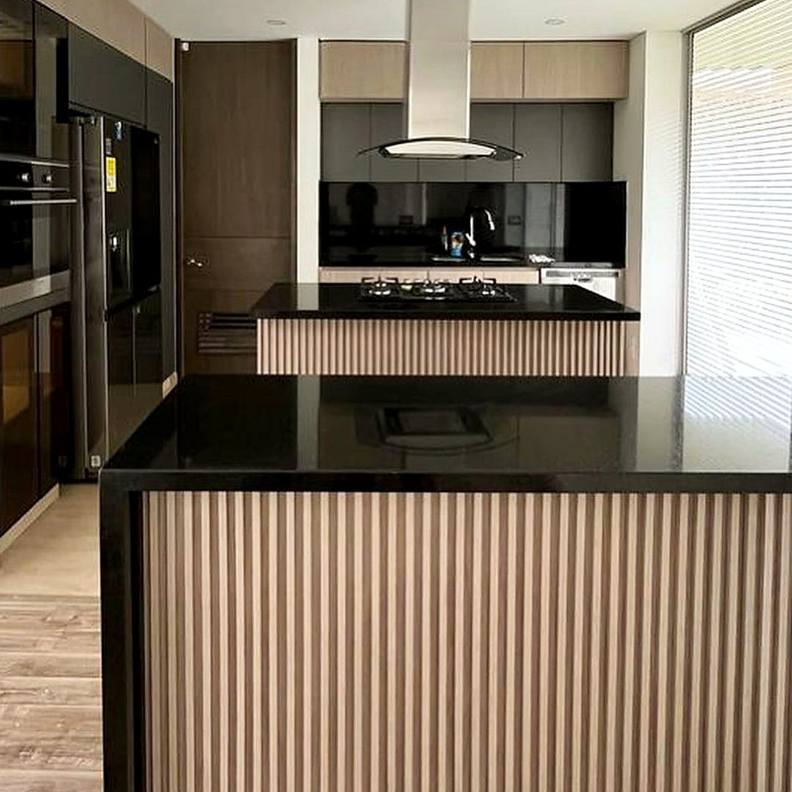 Cocina a la medida con isla en madera ranurada y mesón negro